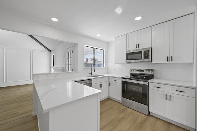 kitchen featuring light stone counters, stainless steel appliances, sink, and white cabinets