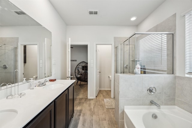 bathroom with independent shower and bath, wood-type flooring, and vanity