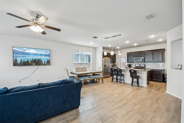 living room with ceiling fan and light hardwood / wood-style flooring