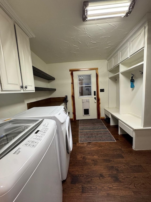 clothes washing area featuring dark wood-type flooring, washer and clothes dryer, and cabinets