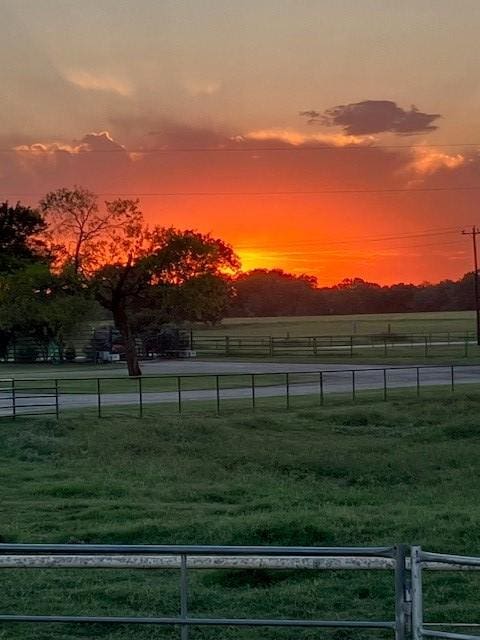 yard at dusk featuring a rural view