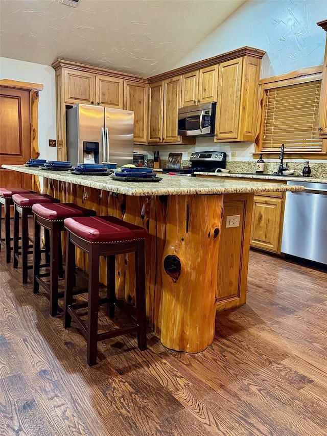 kitchen featuring lofted ceiling, a center island, dark hardwood / wood-style floors, a kitchen breakfast bar, and stainless steel appliances