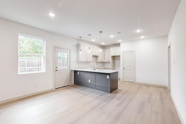 kitchen with a peninsula, light countertops, white cabinetry, pendant lighting, and a sink