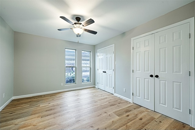 unfurnished bedroom featuring multiple closets, ceiling fan, and light hardwood / wood-style flooring