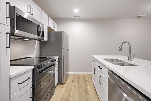 kitchen featuring sink, stainless steel appliances, light stone countertops, light hardwood / wood-style floors, and white cabinets