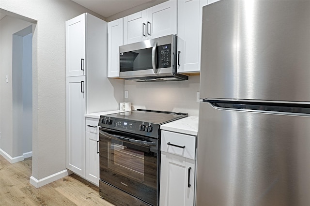 kitchen featuring appliances with stainless steel finishes, light stone countertops, light hardwood / wood-style floors, and white cabinets