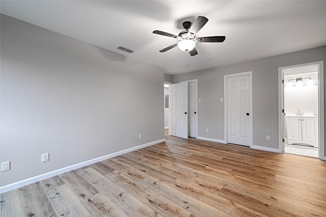 unfurnished bedroom featuring multiple closets, ensuite bathroom, ceiling fan, and light hardwood / wood-style flooring