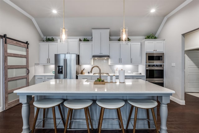 kitchen featuring a barn door, decorative light fixtures, stainless steel appliances, a large island, and white cabinets