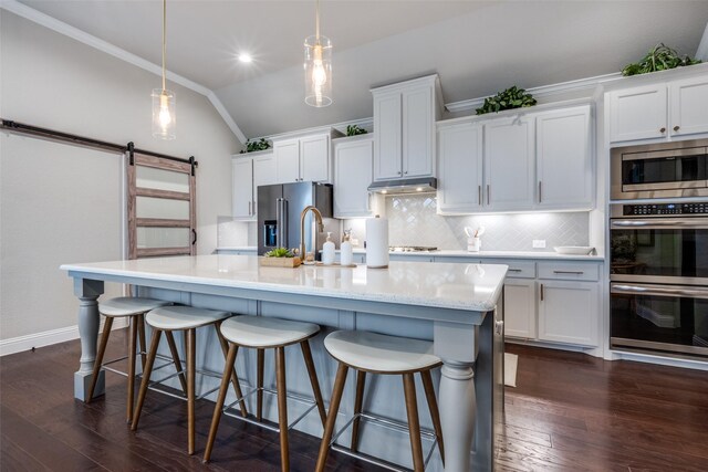 kitchen featuring hanging light fixtures, ornamental molding, an island with sink, stainless steel appliances, and white cabinets