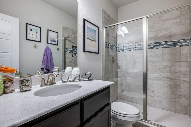 bathroom featuring vanity, toilet, and a shower with shower door