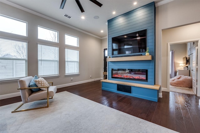 living room with ornamental molding, dark hardwood / wood-style flooring, ceiling fan, and a fireplace