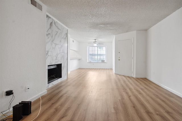 spare room with a textured ceiling, ceiling fan, baseboards, and light wood finished floors