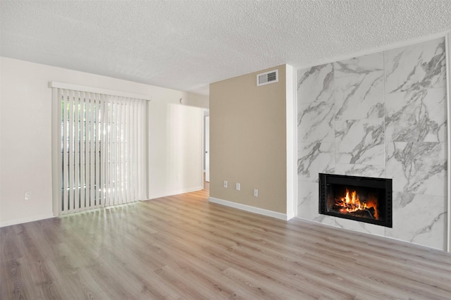 unfurnished living room with a fireplace, a textured ceiling, and light wood-type flooring