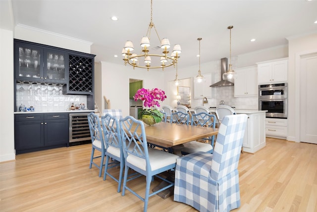 dining space featuring wine cooler, an inviting chandelier, crown molding, and light hardwood / wood-style floors