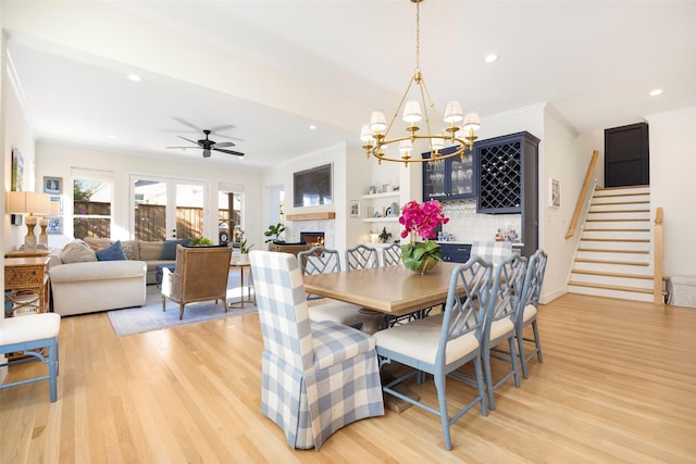 dining area with crown molding, ceiling fan with notable chandelier, and light hardwood / wood-style floors