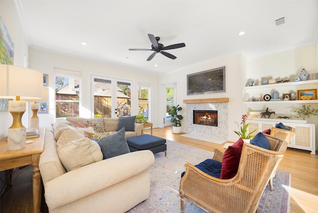 living room with ornamental molding, light hardwood / wood-style floors, and a tile fireplace