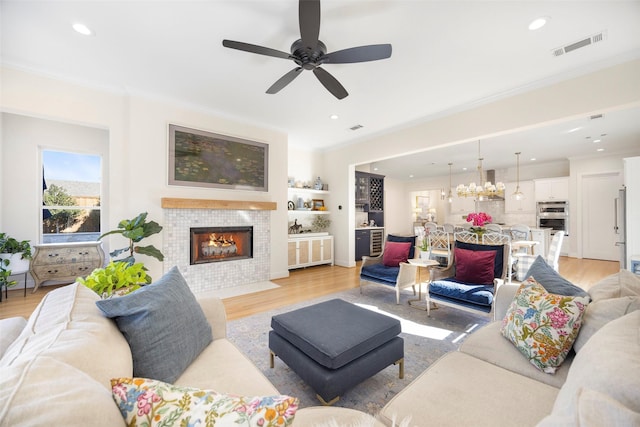 living room with crown molding, light hardwood / wood-style floors, and a tile fireplace