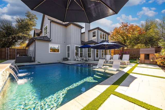 view of pool featuring pool water feature, a storage unit, and a patio area