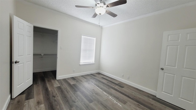 unfurnished bedroom featuring dark hardwood / wood-style flooring, ornamental molding, a spacious closet, and a textured ceiling