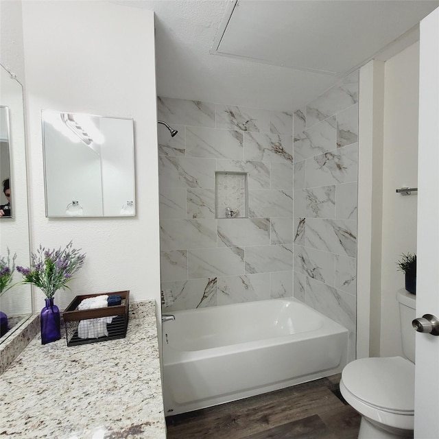 bathroom featuring tiled shower / bath, hardwood / wood-style floors, and toilet