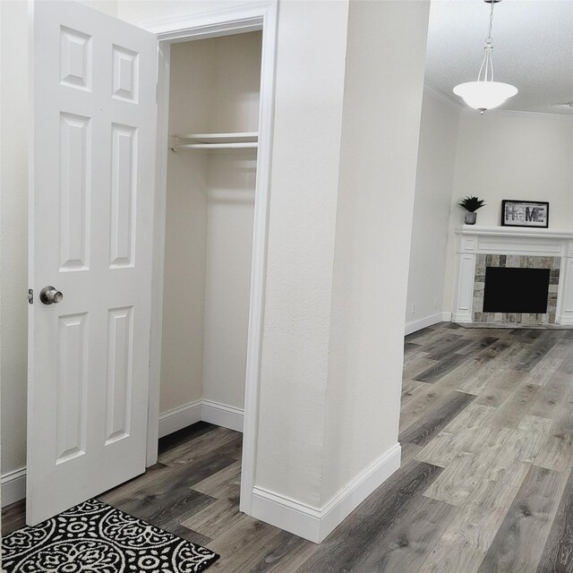 unfurnished living room featuring ceiling fan, a fireplace, ornamental molding, a textured ceiling, and dark hardwood / wood-style flooring