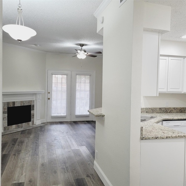 unfurnished living room with ceiling fan, dark wood-type flooring, a fireplace, and a textured ceiling