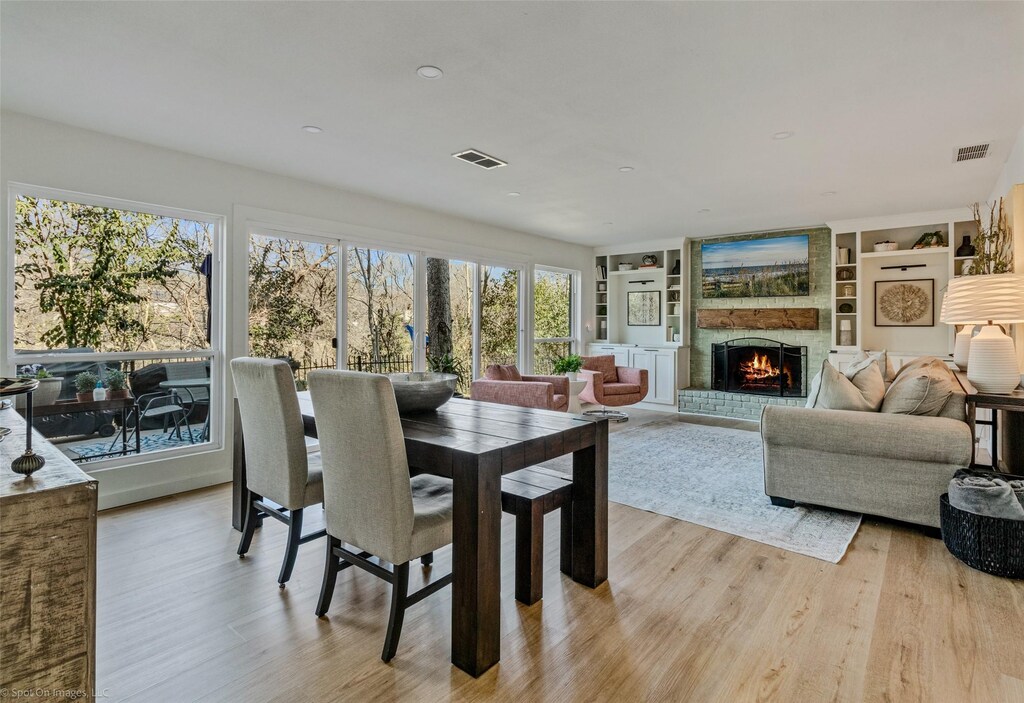 dining space with a brick fireplace, light hardwood / wood-style flooring, and built in features