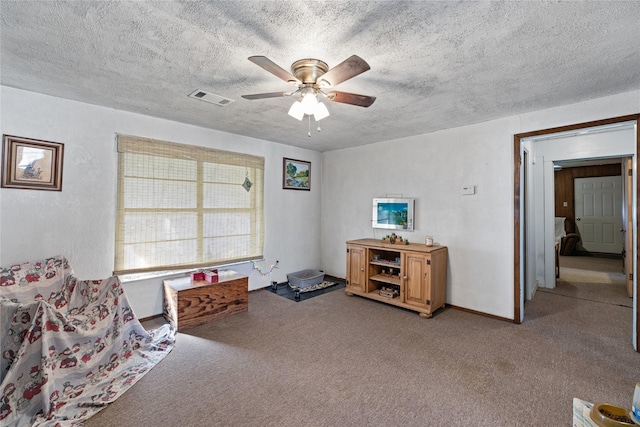 living area featuring ceiling fan, light colored carpet, and a textured ceiling