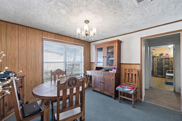 dining room with carpet flooring, a textured ceiling, and wood walls