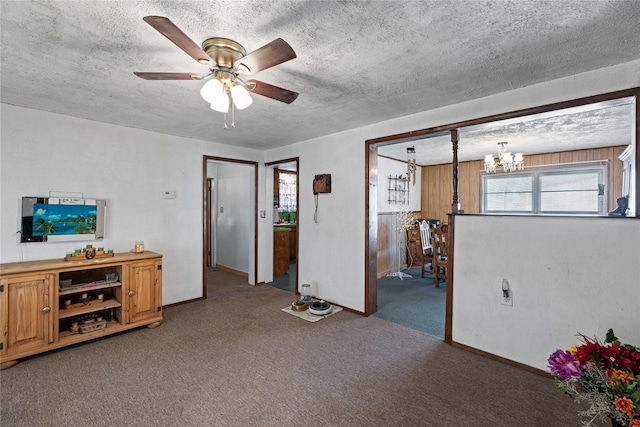 carpeted living room with ceiling fan with notable chandelier and a textured ceiling