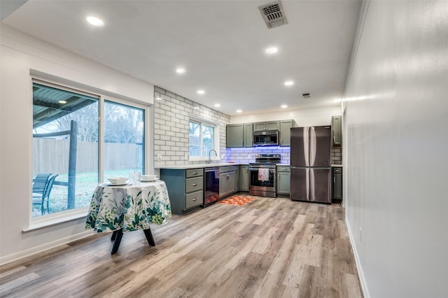 kitchen featuring tasteful backsplash, appliances with stainless steel finishes, sink, and light hardwood / wood-style flooring