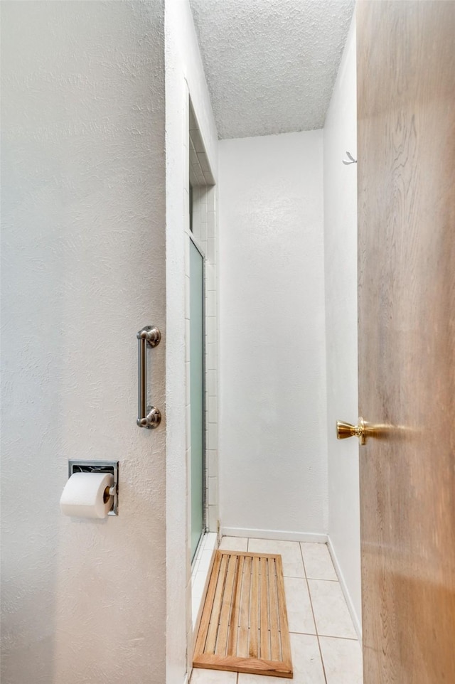 bathroom with tile patterned floors, a textured ceiling, and walk in shower