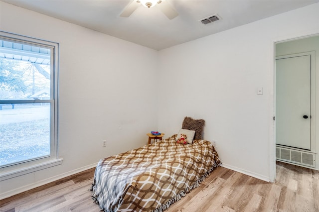 bedroom with multiple windows, light hardwood / wood-style flooring, and ceiling fan