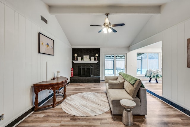 living room with lofted ceiling with beams, hardwood / wood-style floors, and a brick fireplace