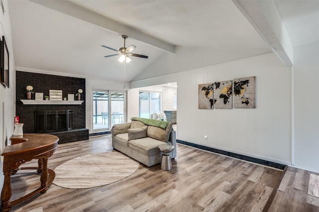 living room featuring lofted ceiling with beams, a brick fireplace, hardwood / wood-style floors, and ceiling fan