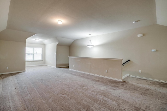 additional living space featuring vaulted ceiling and light carpet