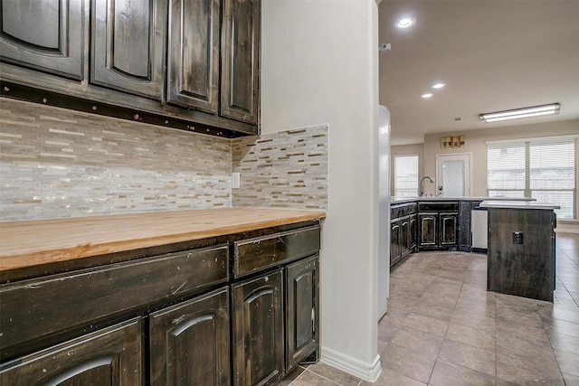 kitchen with dark brown cabinetry, butcher block counters, sink, and decorative backsplash