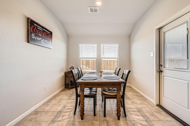 tiled dining area featuring vaulted ceiling