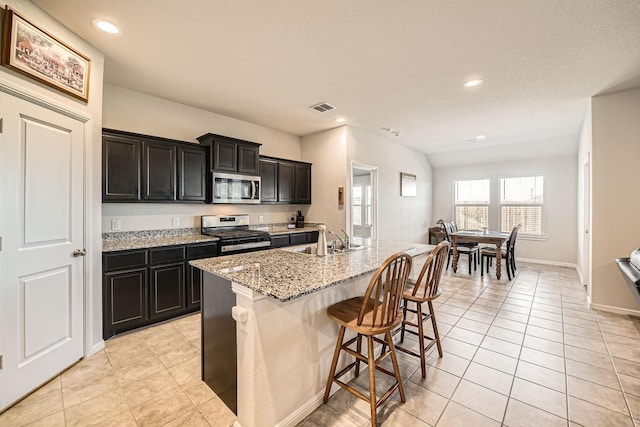 kitchen featuring light tile patterned flooring, appliances with stainless steel finishes, sink, and a kitchen island with sink