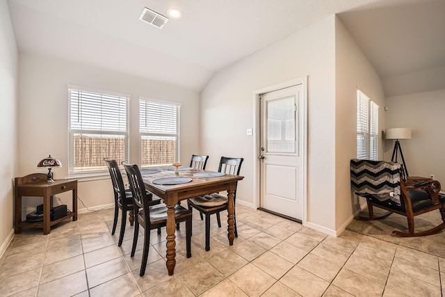 tiled dining room with lofted ceiling and plenty of natural light