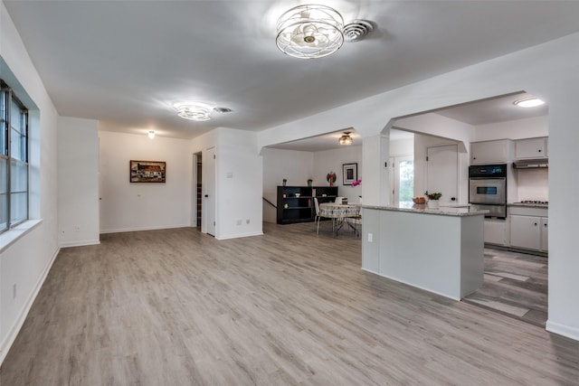 kitchen with appliances with stainless steel finishes, light stone counters, and light hardwood / wood-style floors