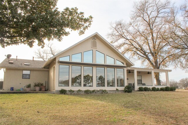 back of property with ceiling fan and a lawn