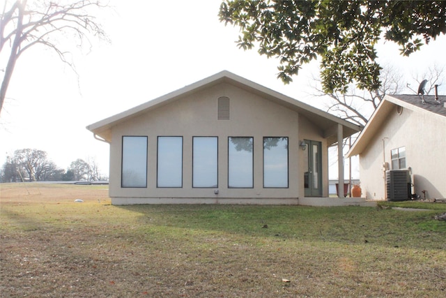 back of property featuring central AC unit and a lawn