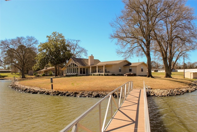 view of dock with a water view and a yard