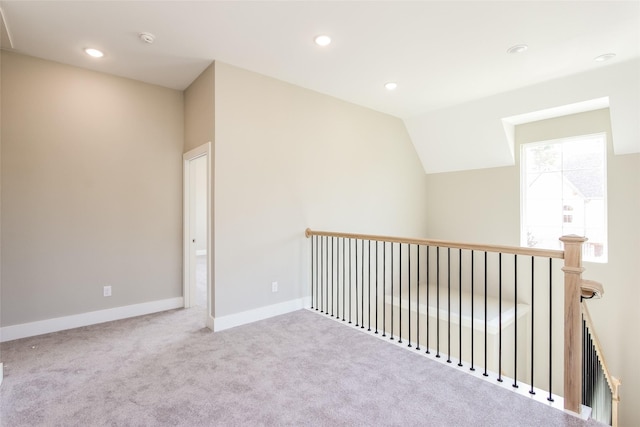 carpeted empty room with vaulted ceiling