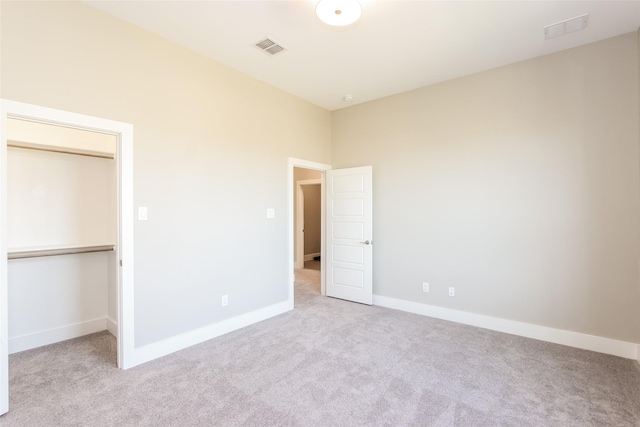 unfurnished bedroom with a closet, light carpet, and a walk in closet