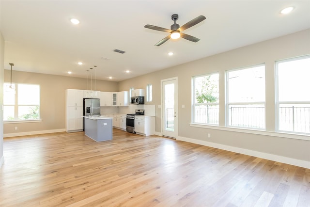 kitchen with a kitchen island, pendant lighting, white cabinets, stainless steel appliances, and a healthy amount of sunlight