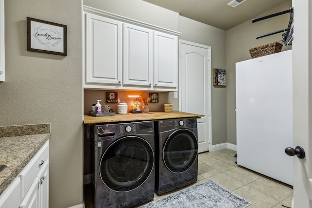 laundry area with cabinets, washing machine and clothes dryer, and light tile patterned floors