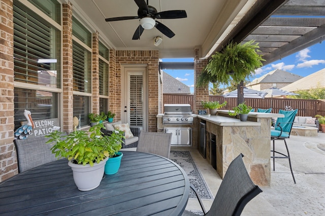 view of patio / terrace featuring ceiling fan, an outdoor kitchen, exterior bar, and area for grilling