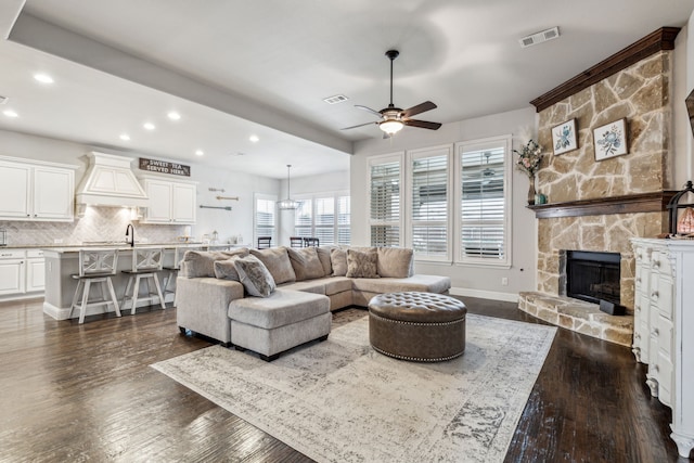 living room featuring ceiling fan, a fireplace, and dark hardwood / wood-style floors